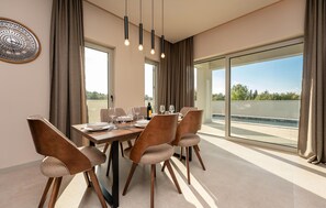 A dining area with a wooden table, four chairs, and a large window with a view of greenery. - Beautiful apartment in Zaton (Zaton)