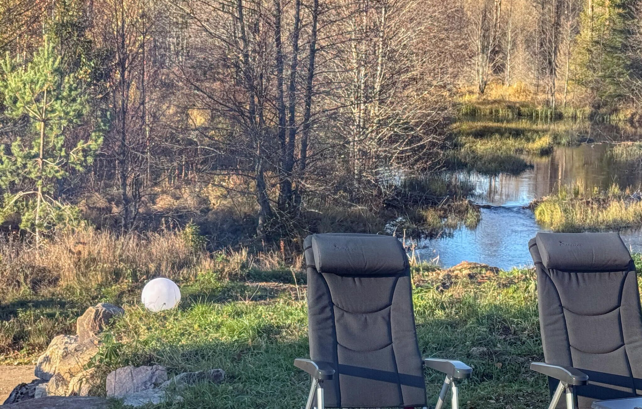 To stole med udsigt til en flod, træer i baggrunden.
