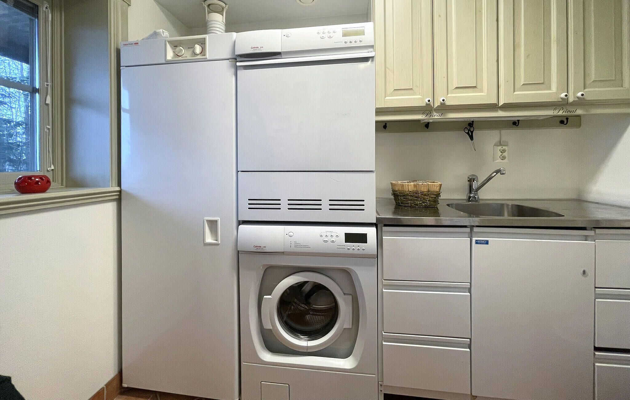 A compact laundry room with a front-loading washer and dryer, a sink, and cabinets.