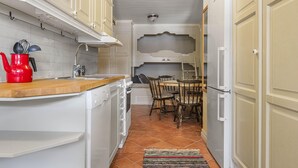 A narrow kitchen with white cabinetry, a wooden countertop, and a tiled backsplash. There is a dining area with a table and chairs, and a refrigerator on the right. - 1 bedroom gorgeous apartment in åre (Åre)