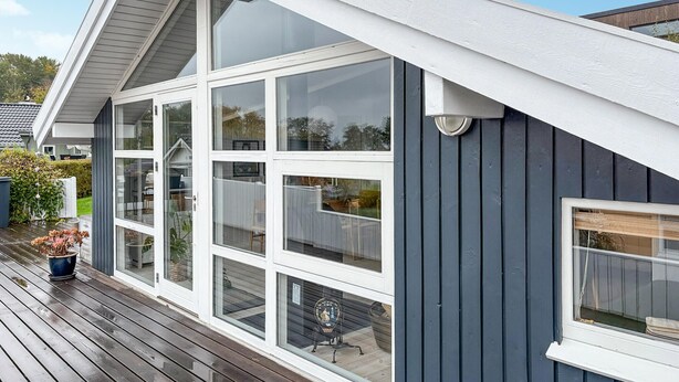 Uma casa moderna com amplas janelas e um deck de madeira.
