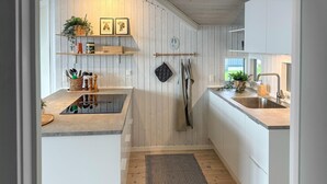 Cozinha moderna com ilha central, piso de madeira e armários brancos.