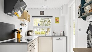 A modern kitchen with white cabinetry, a dishwasher, and a window overlooking greenery. - Amazing home in Tarm with WiFi (Tarm)