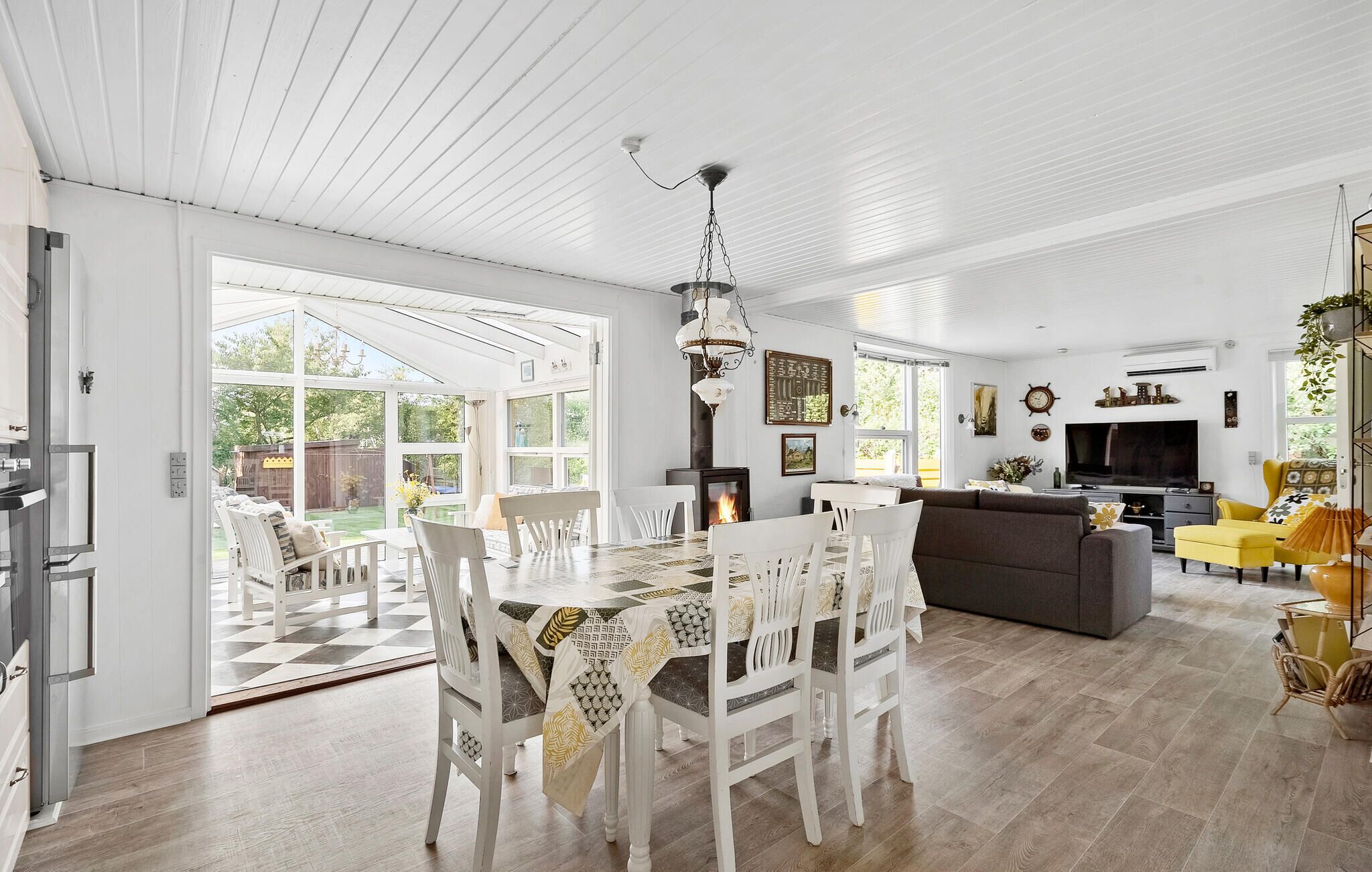 A spacious living area with a dining table, chairs, a sofa, and a TV.