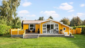 A yellow house with a patio, a dining area, and a large sliding glass door. - Amazing home in Tarm with WiFi (Tarm)