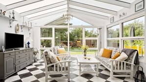 A conservatory with a checkered floor, white furniture, and large windows offering a view of the garden. - Amazing home in Tarm with WiFi (Tarm)