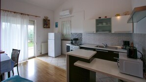 Une cuisine compacte équipée d’un réfrigérateur, d’une cuisinière, d’un évier et d’un four à micro-ondes. Un coin repas avec une table et des chaises est également disponible.
