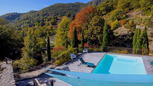 A pool area with a wooden deck, lounge chairs, and a view of a mountainous landscape. - Pet friendly home in Genestelle (Genestelle)