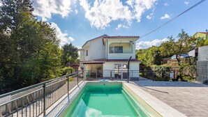 Une maison à deux étages avec une piscine dans le jardin.