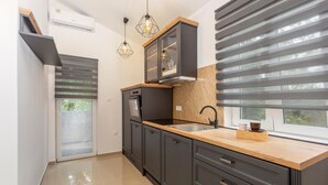 Une cuisine moderne avec des meubles de couleur sombre, un plan de travail en bois et un four encastré.