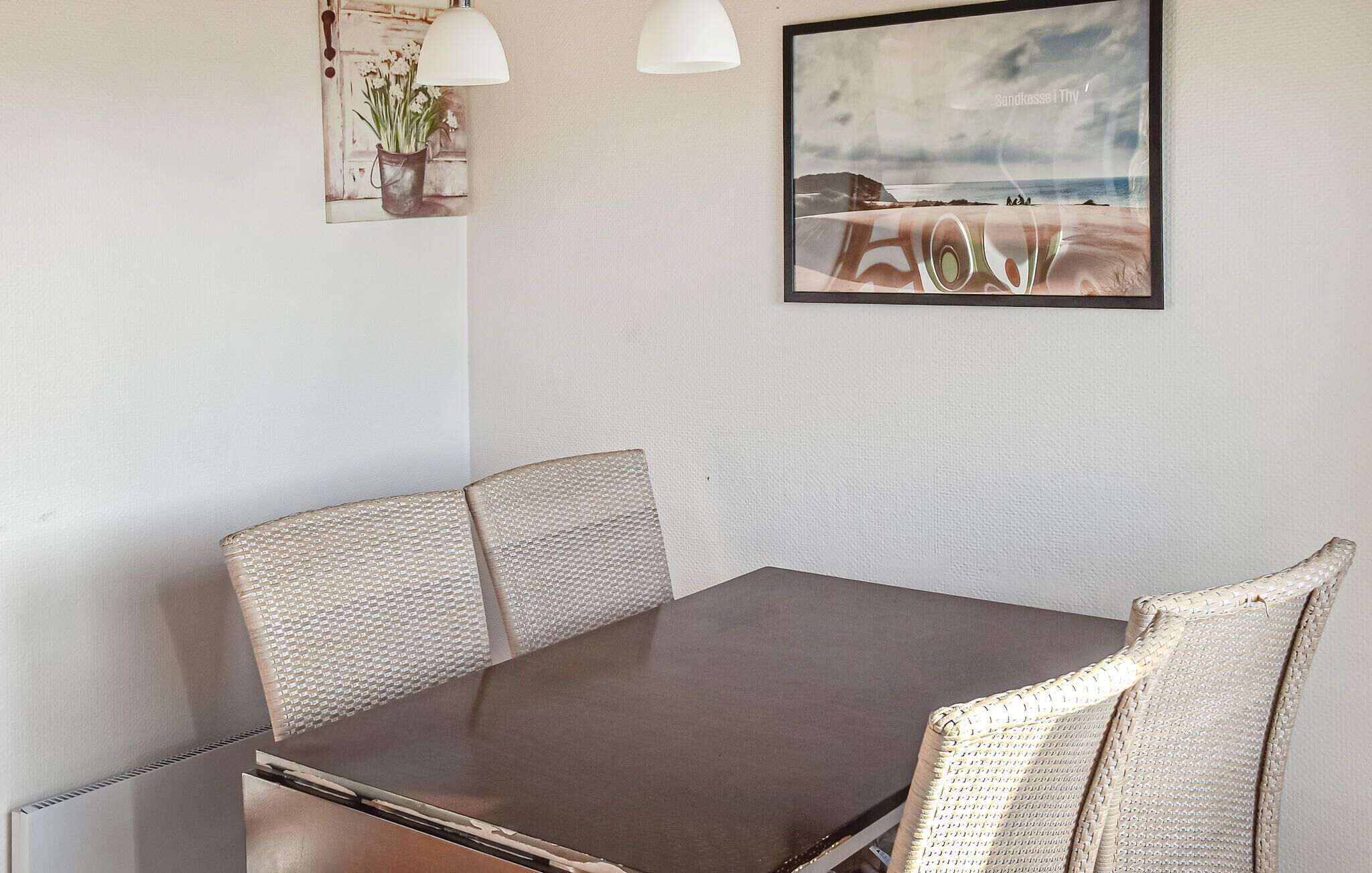 Un comedor con una mesa de madera oscura y sillas tejidas.