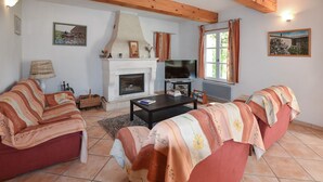 Ein Wohnzimmer mit Kamin, Sofagarnitur, Fernseher und Kunstwerken an den Wänden.