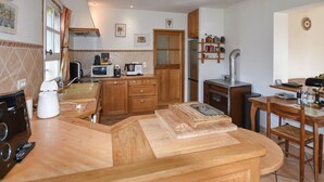 Eine kleine Küche mit Holzausstattung, einer Mikrowelle, einem Herd und einer Essecke mit Holztisch und Stühlen.