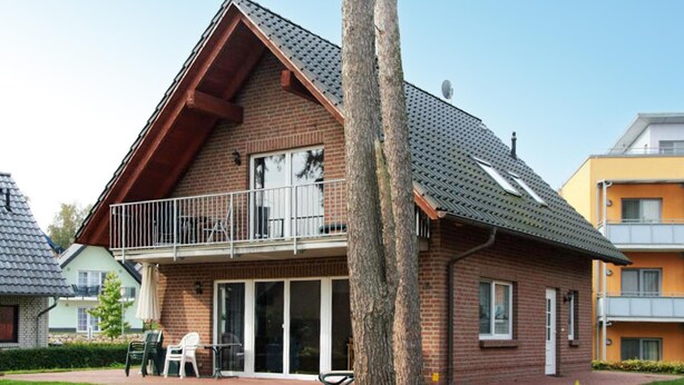 Een woonhuis met twee verdiepingen, een balkon, een bakstenen gevel en een pannendak.