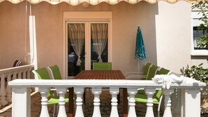 An outdoor patio with a white table and green chairs, a blue umbrella, and a white railing. - 2 bedroom nice apartment in Vir (Vir)