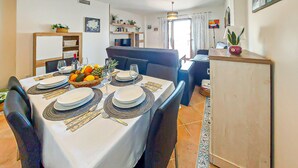 A dining area with a table set for four, chairs, a refrigerator, and a kitchen in the background. - Amazing apartment in Costa Esuri - Ayamonte (Costa Esuri - Ayamonte)