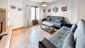 A living room with a sofa, a coffee table, a TV, and a door leading to a balcony. - Amazing apartment in Costa Esuri - Ayamonte (Costa Esuri - Ayamonte)