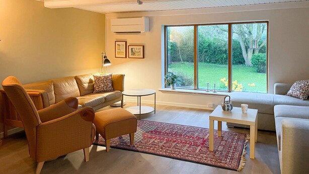 A living room with a sofa, armchairs, a coffee table, and a large window with a view of greenery. - 3 bedroom gorgeous home in søby ærø (Søby Ærø)