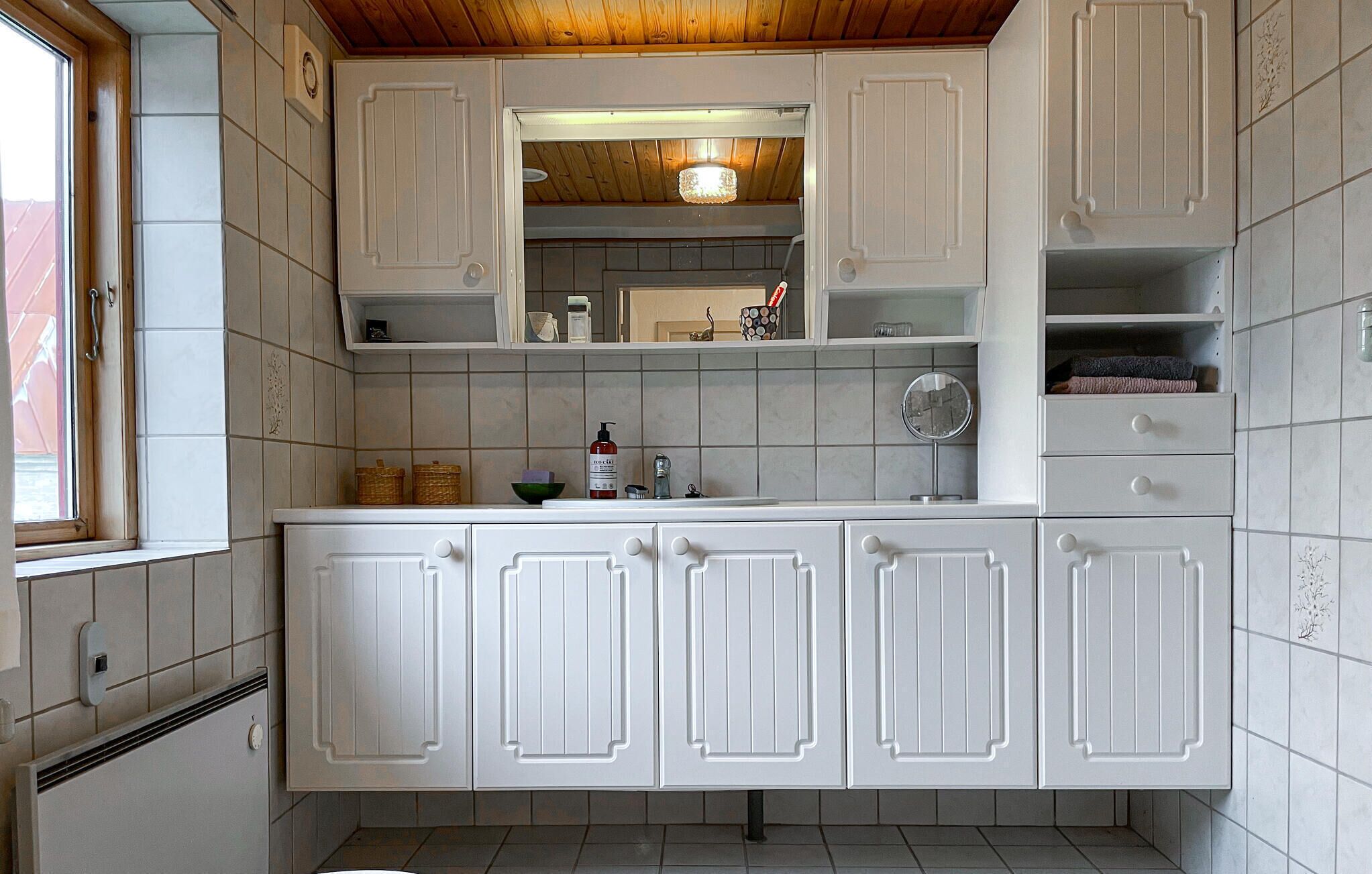 A kitchen with white cabinets, a window, and a wooden ceiling.