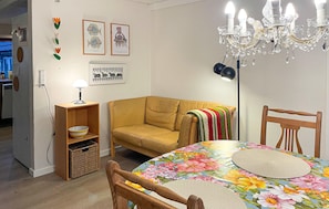 A living room with a sofa, a table with a floral tablecloth, a chandelier, and wall art.