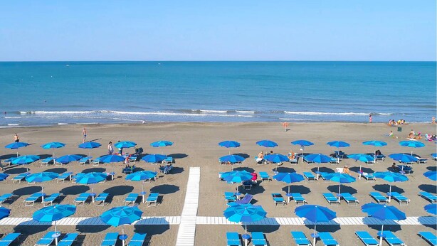 A beach with rows of blue umbrellas and sun loungers, a clear sky, and the ocean in the background. - Cozy home in Tarquinia with swimming pool (Tarquinia)