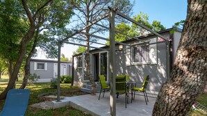 En patio med pergola, udendørs møbler og en lille bygning med et vindue.