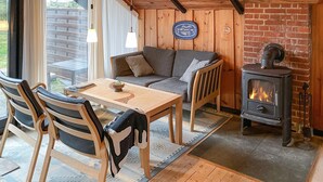 A cozy room with a sofa, wooden table, chairs, and a wood-burning stove. - Amazing home in Humble with WiFi (Humble)