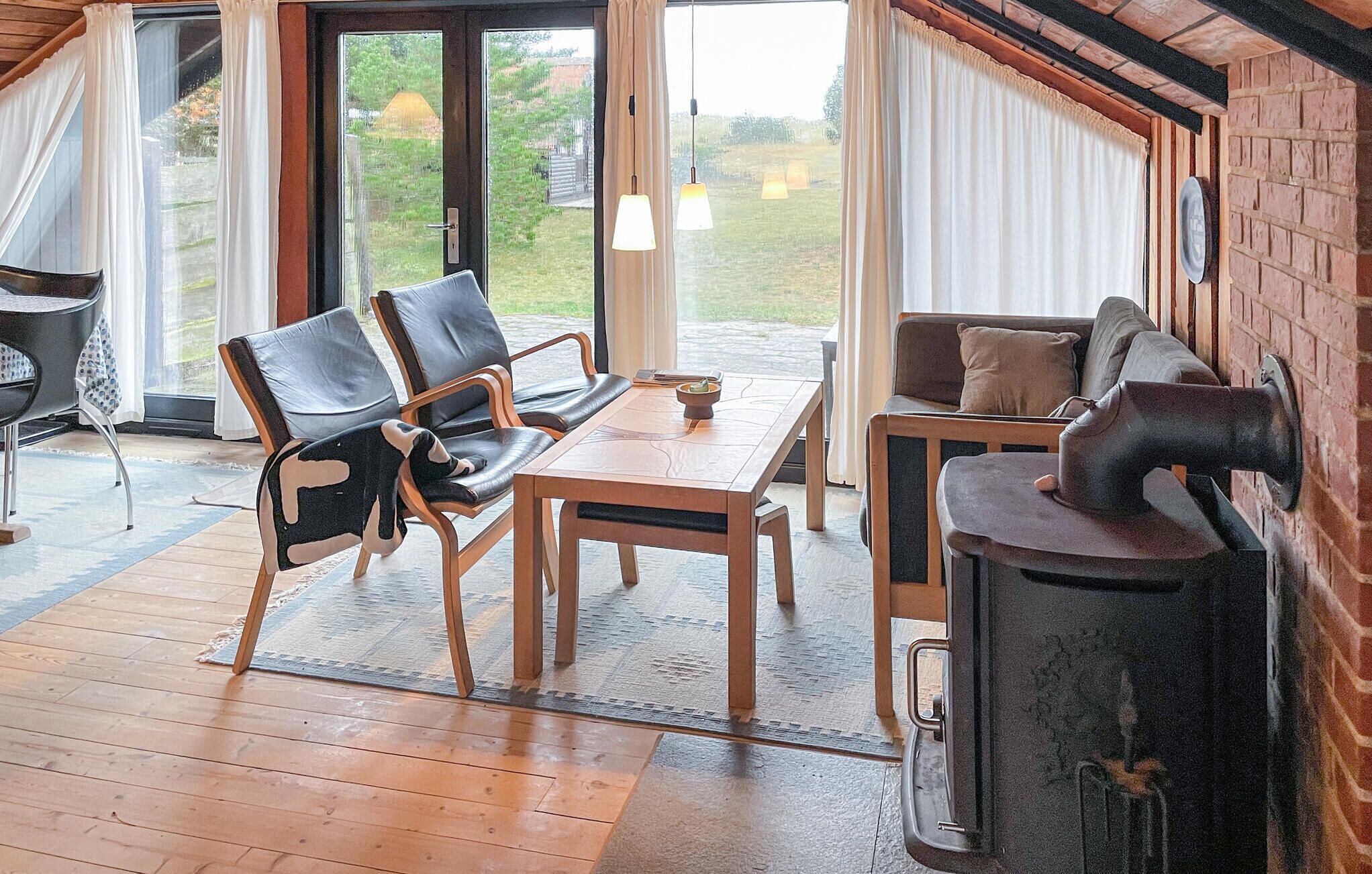 Une pièce chaleureuse avec une table en bois, deux chaises, un canapé et une cheminée.