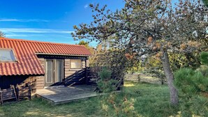 A rustic cabin with a red metal roof, a wooden deck, and a small porch. - Amazing home in Humble with WiFi (Humble)