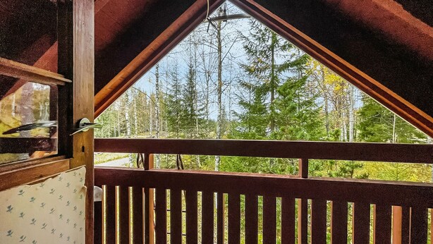Un balcón de madera con vistas a una zona boscosa.