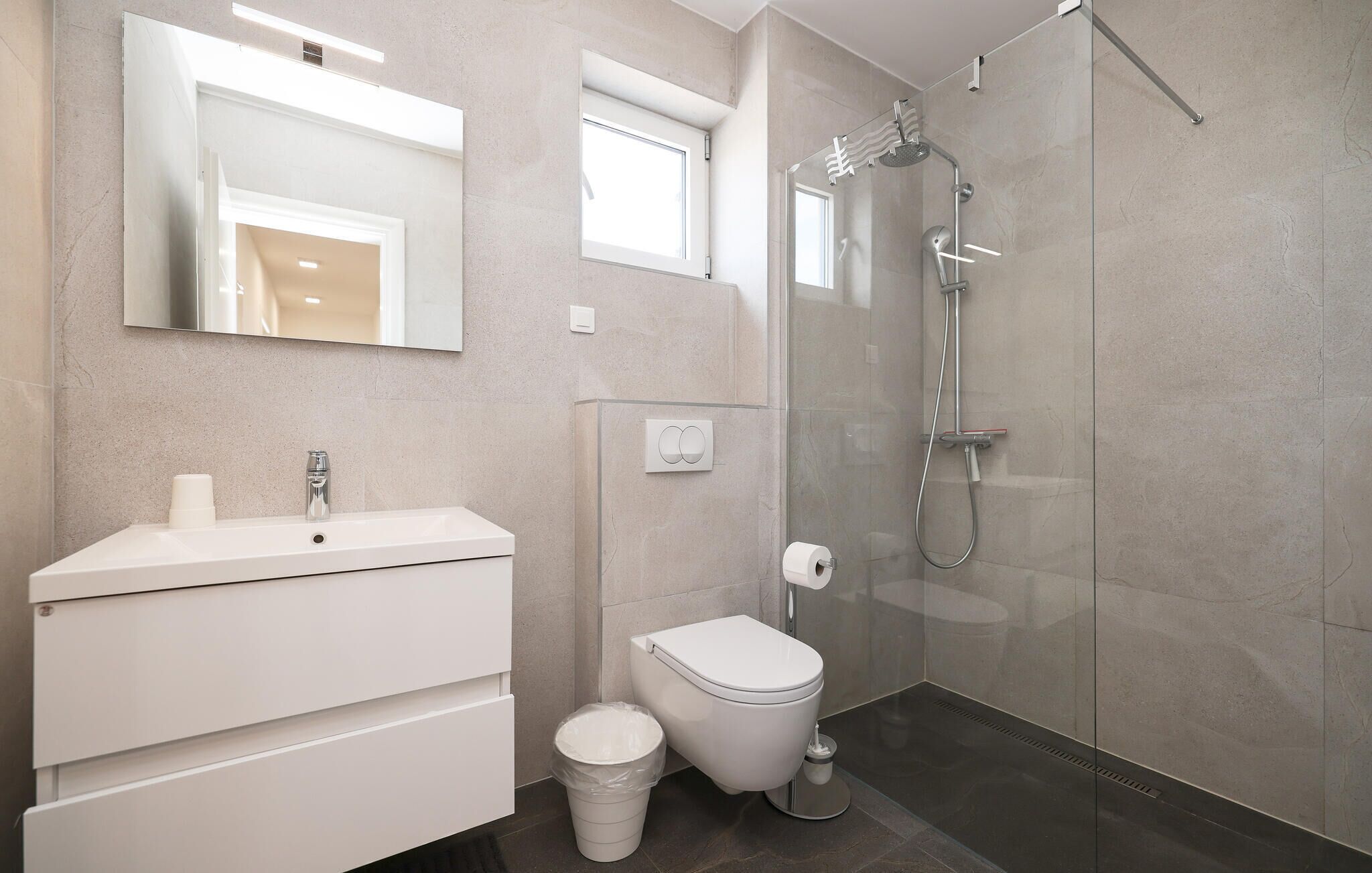 Un baño moderno con tocador blanco, inodoro y cabina de ducha con vidrio.
