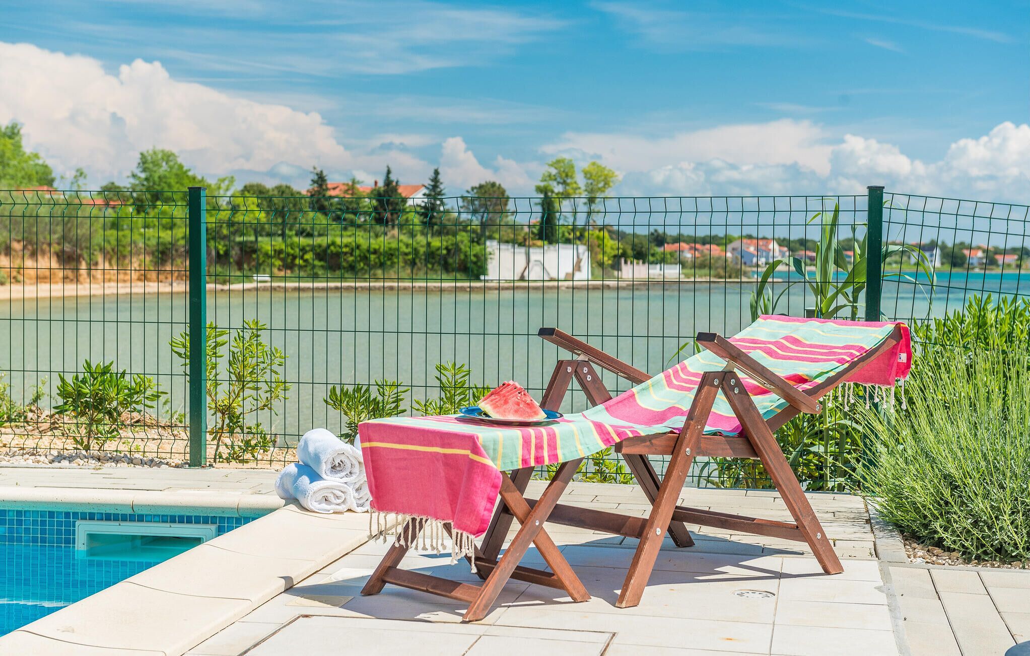 Un espace aménagé au bord de la piscine, comprenant deux chaises longues, une serviette et une petite table.