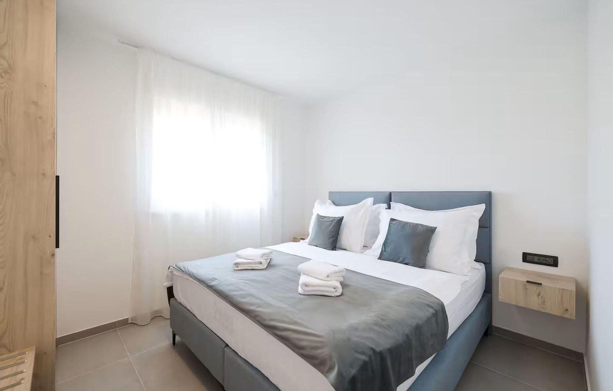 Ein modernes Schlafzimmer mit einem Bett, Kissen und einem Nachttisch.