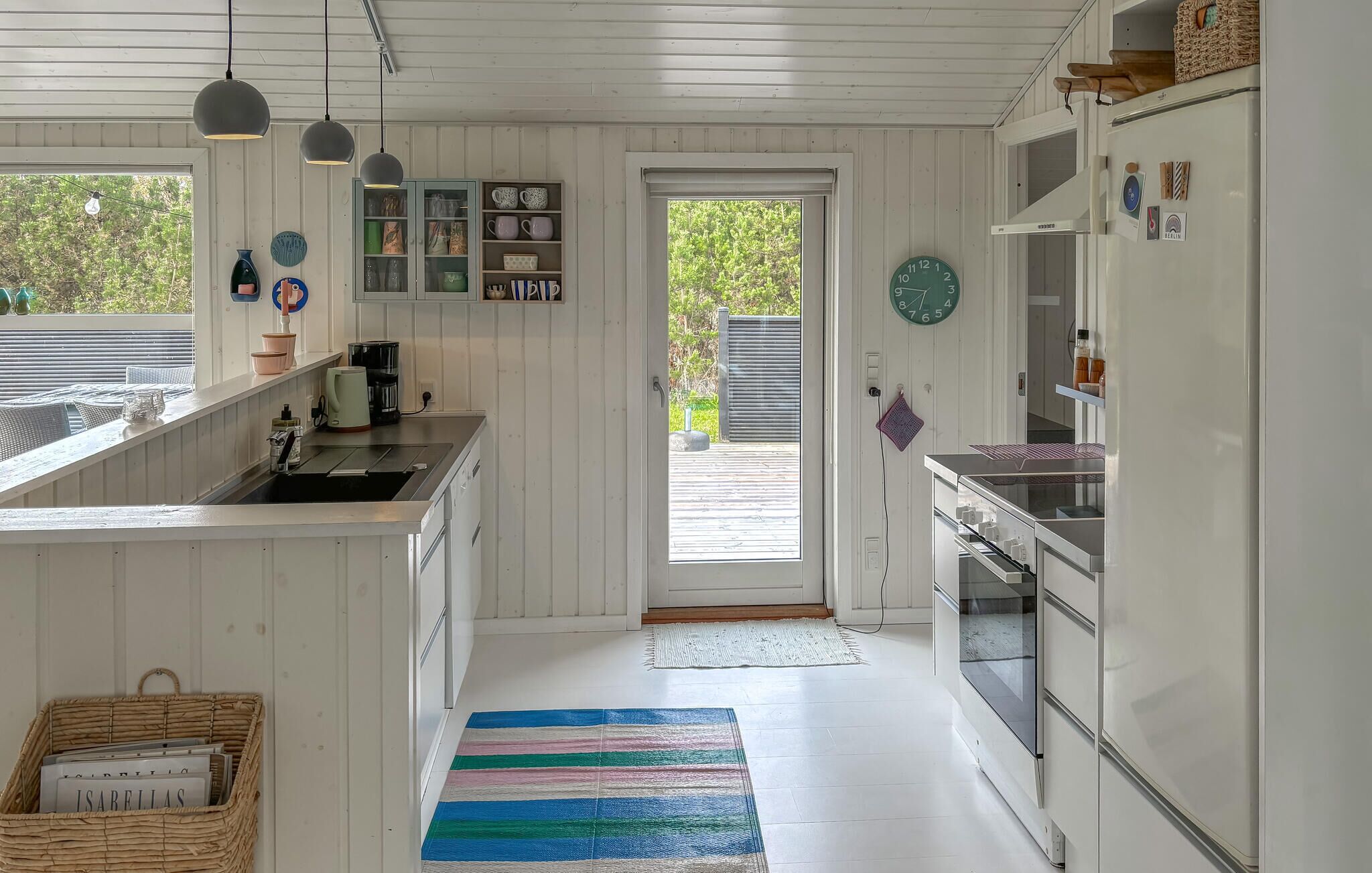 A kitchen with white cabinets, a coffee maker, and a striped rug.
