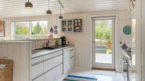 A kitchen with white cabinets, a coffee maker, and a window overlooking greenery. - Lovely home in Fjerritslev with WiFi (Fjerritslev)