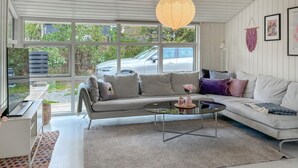 A modern living room with a grey sofa, a glass coffee table, and a view of a car and greenery outside. - Lovely home in Fjerritslev with WiFi (Fjerritslev)