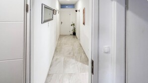 A hallway with a tiled floor, a door at the end, and a potted plant. - 1 bedroom amazing apartment in Duce (Duce)