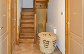 A narrow hallway with a wooden staircase, a woven basket, and a radiator.