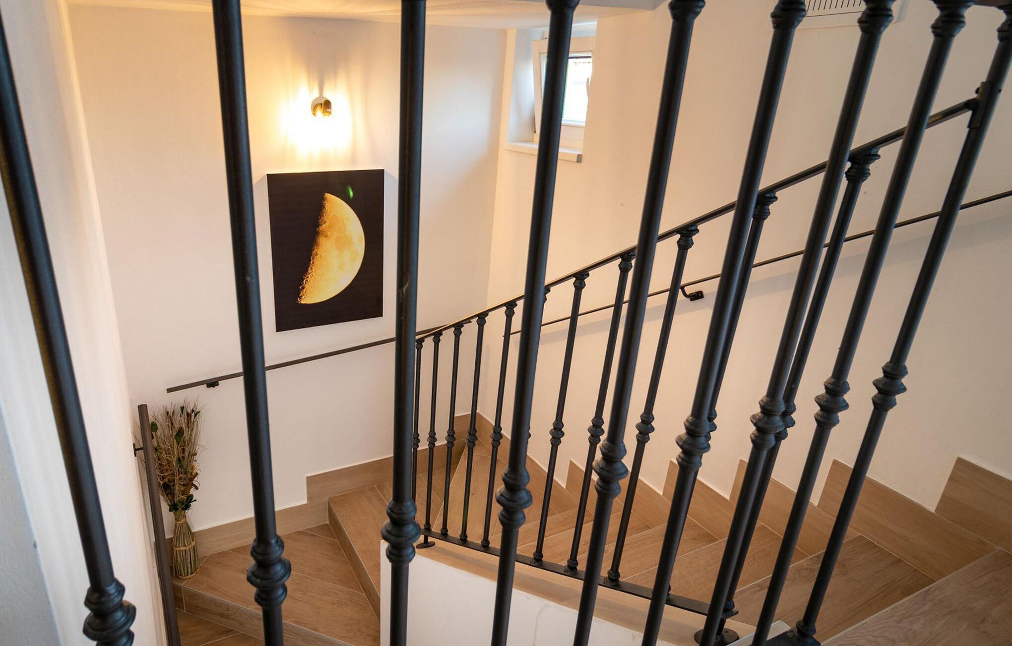 Una escalera con barandillas negras y escalones de madera.