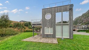 Een moderne houten blokhut met een rond raam, een schotelantenne en een terras.