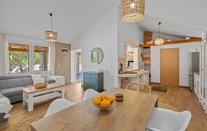 Ein geräumiger Wohnbereich mit Sofa, Esstisch und Küche.
