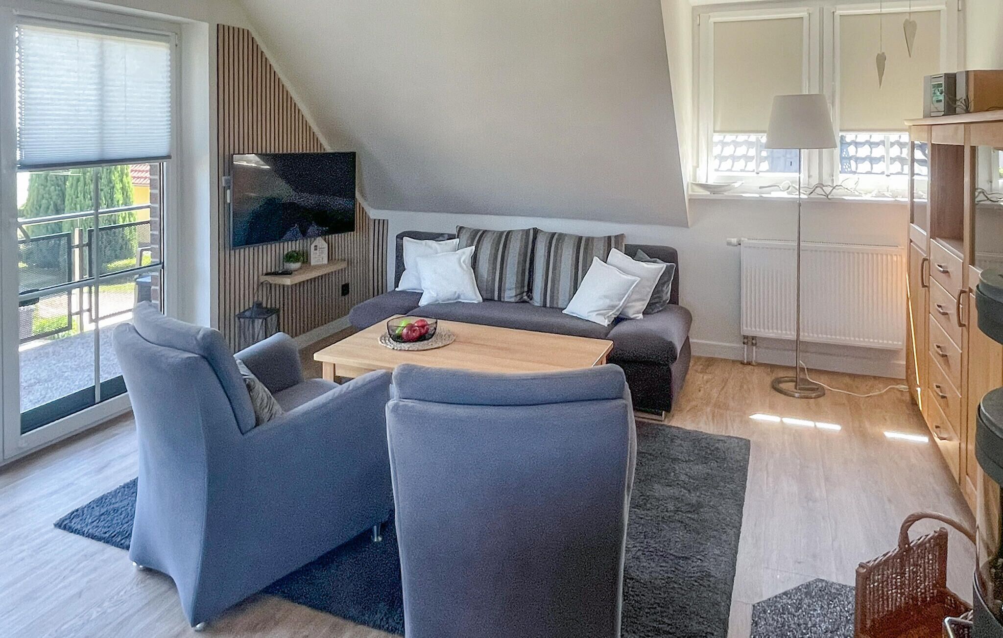 Un salon moderne comprenant un canapé, deux fauteuils, une table basse et un téléviseur.