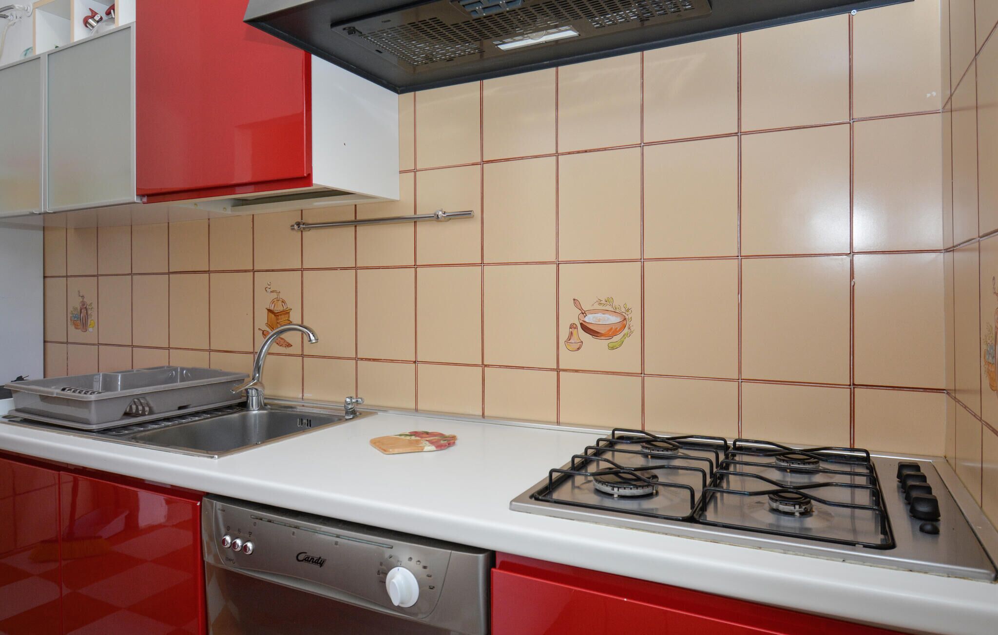 A kitchen with a gas stove, a sink, and red cabinets.