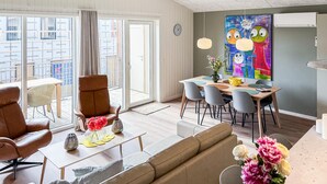 Una sala de estar moderna con un sofá, sillas, una mesa de comedor y un ventanal grande.