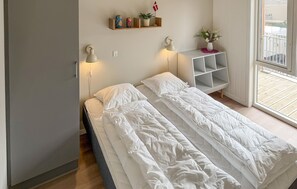 Ein Schlafzimmer mit zwei Betten, Nachttischlampen, einer kleinen Ablage mit Dekoration und einem Fenster mit Blick.