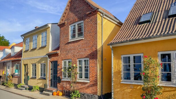 Uma fileira de casas tradicionais em estilo europeu, com fachadas de tijolo e telhados inclinados.