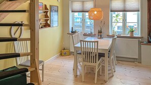 Uma área de refeições com escada de madeira, uma mesa com cadeiras e um lustre.