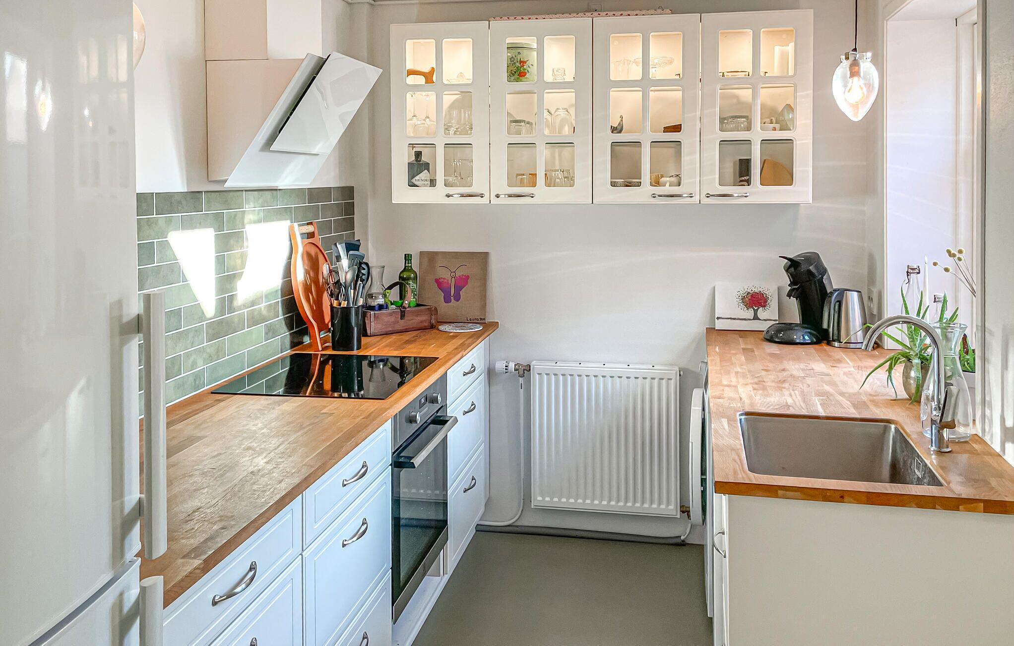 A modern kitchen with white cabinets, a wooden countertop, and a built-in oven.