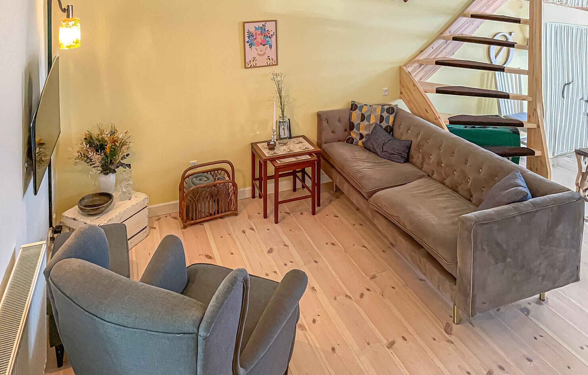 Ein Wohnzimmer mit einer Couch, zwei Sesseln, einem kleinen Tisch mit einer Vase und einem dekorativen Wandbild.