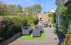 Ein Patio im Freien mit Steinmauern, einem Steinkamin und Korbmöbeln.